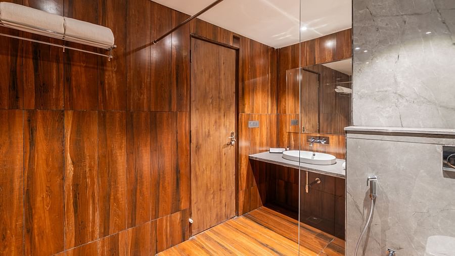 Deluxe King Room bathroom with wooden accents, marble sink, and modern lighting at Clarks Inn Suites Jaipur, Ajmer Road
